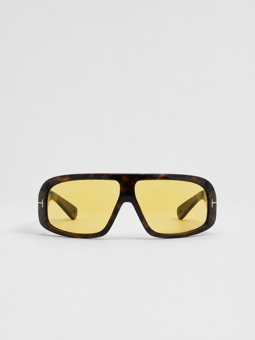 A pair of oversized shield sunglasses with a dark brown tortoiseshell frame and yellow tinted lenses, shown against a plain light gray background.